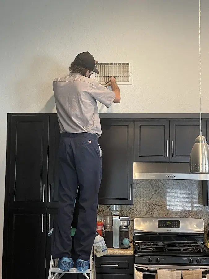 Technician inspecting an air vent during HVAC service in Mayfair